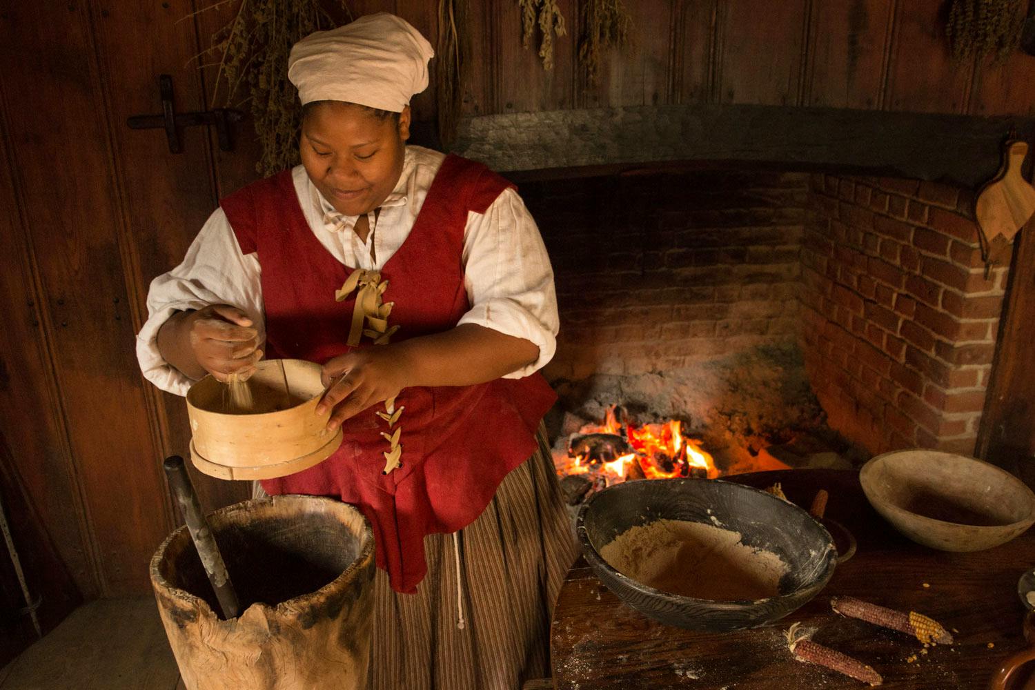 An indentured servant is preparing a meal in the main room of the hose at the Godiah Spray Tobacco Plantation