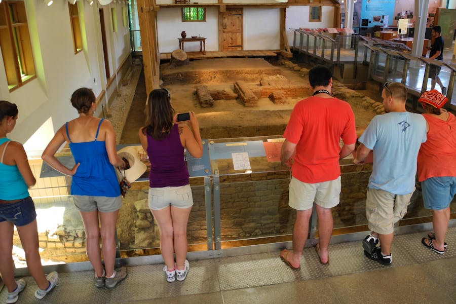 A group of visitors looks at the archaeological remains of house built in the 1600's