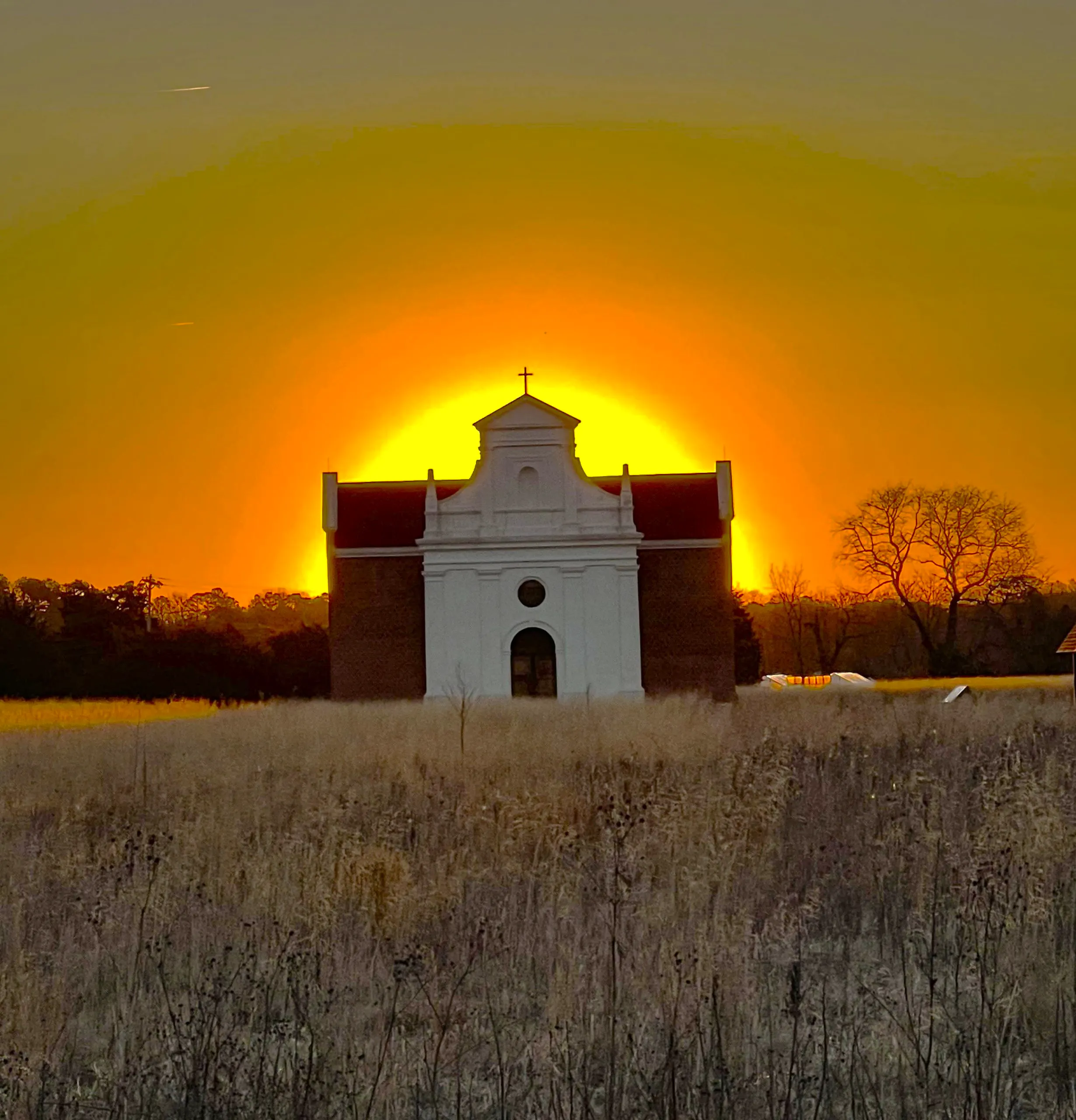 A sunrise directly behind the brick chapel.